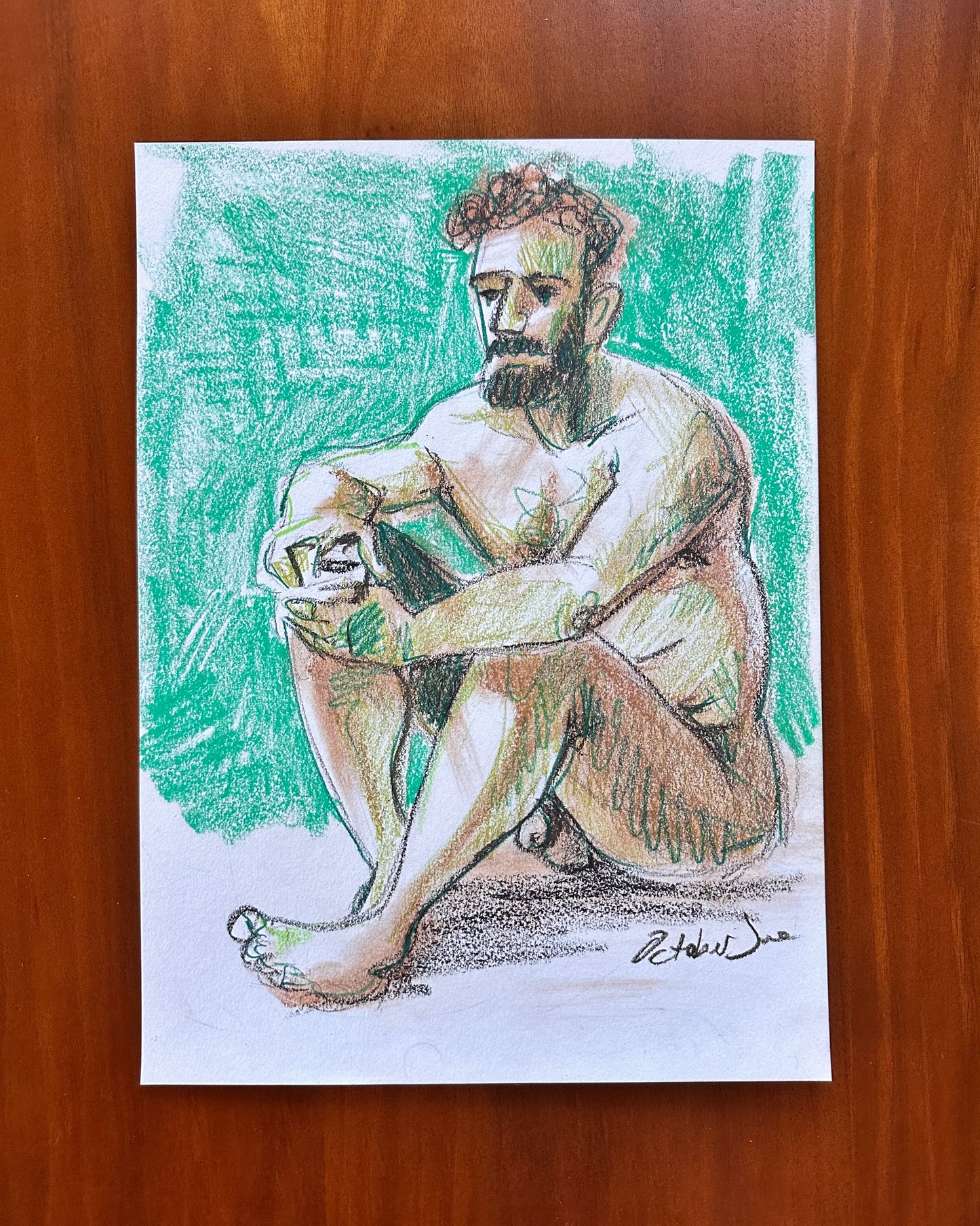 Colorful drawing of a seated figure on a wooden surface
