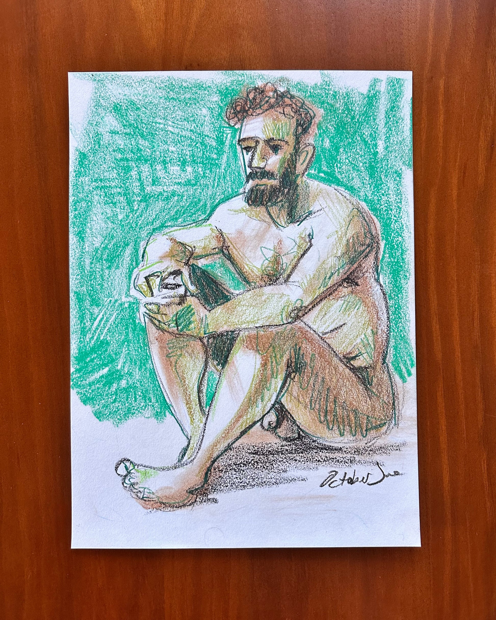 Colorful drawing of a seated figure on a wooden surface