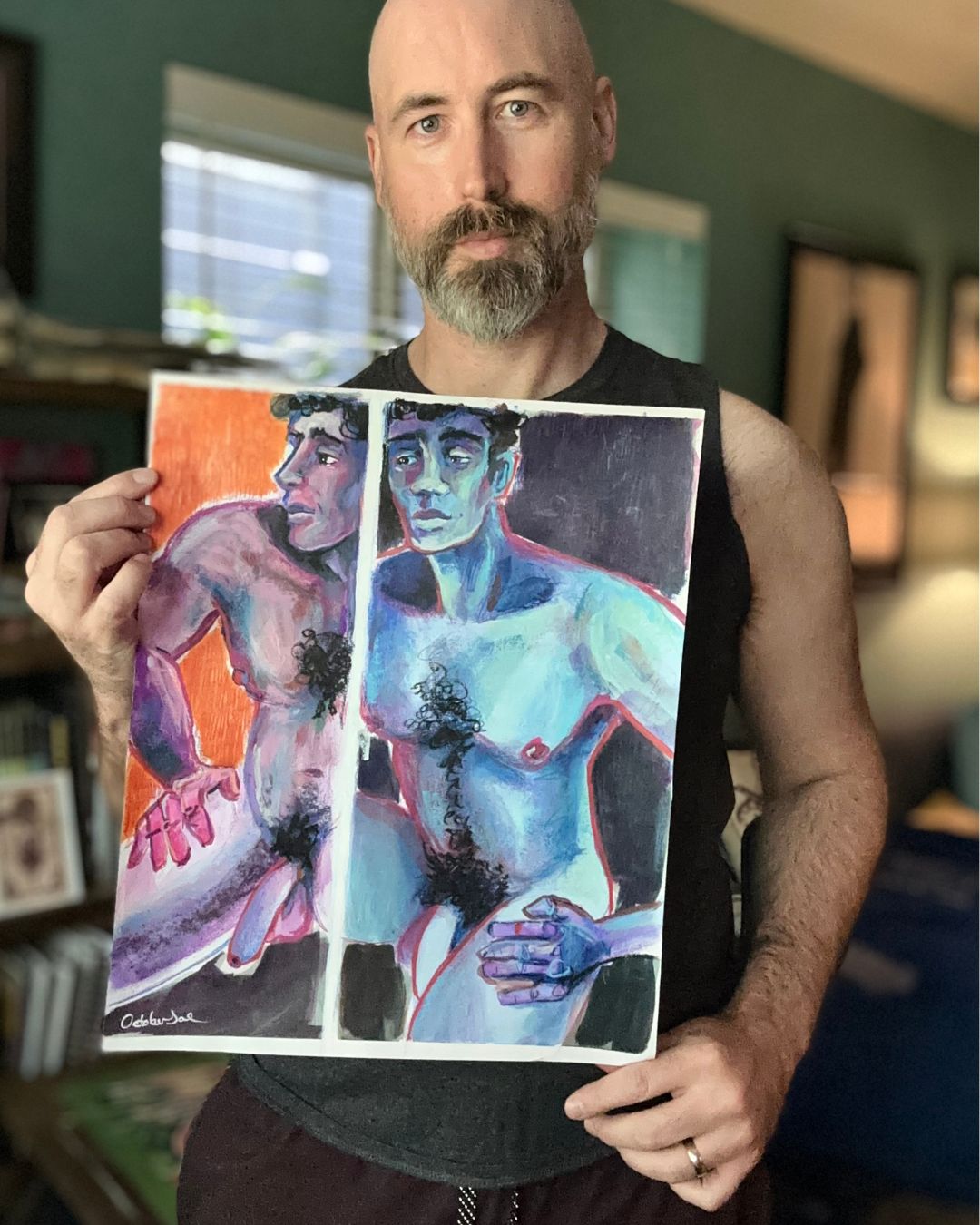 Man holding a painting of two figures in a room with books and decor.